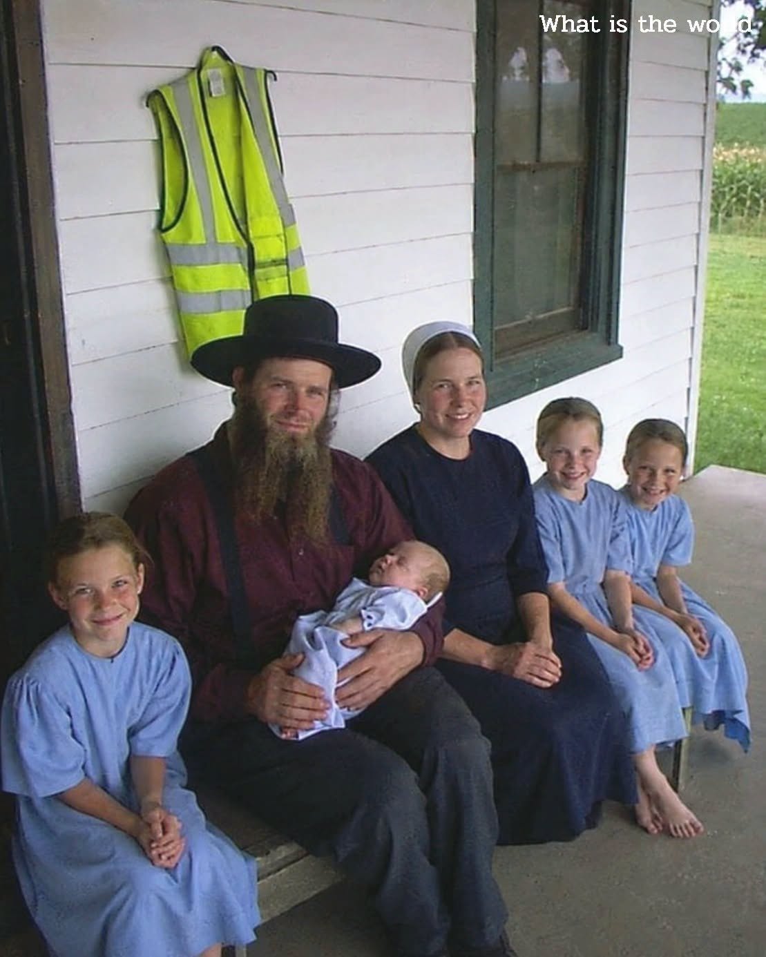 An old photograph of an Amish family standing in front of a red barn with a mysterious door in the background